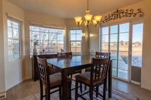 Dining room featuring plenty of natural light, wood-style floors, and a chandelier