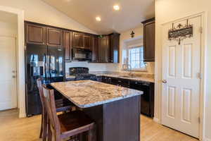 Kitchen with light wood-type flooring, granite countertops and a kitchen island