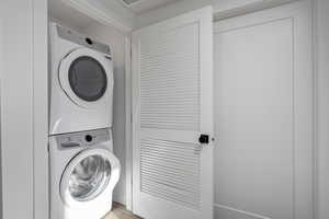 Laundry room featuring stacked washing maching and dryer and light hardwood / wood-style flooring