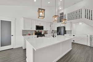 Kitchen featuring sink, black appliances, hanging light fixtures, and white cabinets