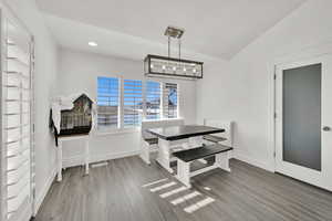 Dining space with lofted ceiling, a notable chandelier, and dark wood-type flooring