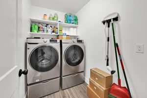 Laundry area featuring independent washer and dryer and light hardwood / wood-style flooring