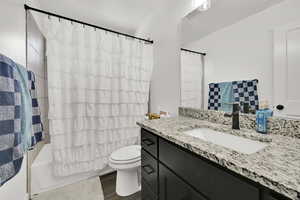 Full bathroom featuring vanity, toilet, hardwood / wood-style floors, and shower / bath combo with shower curtain