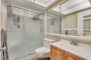 Bathroom featuring walk in shower, vanity, and toilet