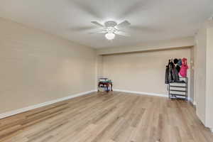 Spare room featuring ceiling fan, brick wall, and light hardwood / wood-style floors