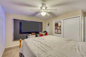 Bedroom with light colored carpet, ceiling fan, and a closet