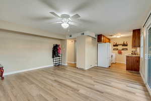 Unfurnished living room with ceiling fan, washer / dryer, and light wood-type flooring