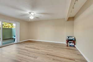 Spare room with brick wall, ceiling fan, and light wood-type flooring