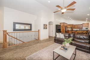 Living room with ceiling fan and high vaulted ceiling