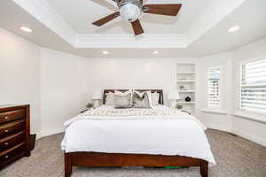 Carpeted bedroom with ornamental molding, a raised ceiling, and ceiling fan