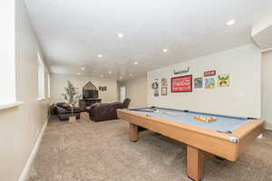 Playroom with carpet flooring, a textured ceiling, and billiards