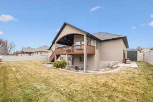 Rear view of property featuring a wooden deck, a yard, a patio area, and a shed