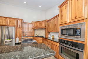 Kitchen featuring tasteful backsplash, appliances with stainless steel finishes, sink, and dark stone countertops