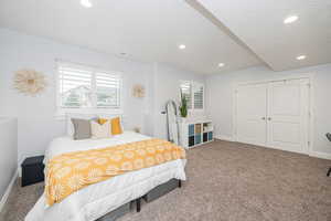 Bedroom with multiple windows, a textured ceiling, and carpet flooring