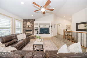 Living room featuring lofted ceiling, a fireplace, built in features, and ceiling fan