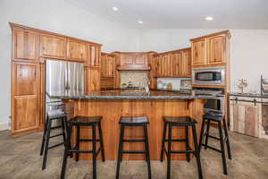 Kitchen with backsplash, stainless steel appliances, a kitchen breakfast bar, high vaulted ceiling, and a center island with sink