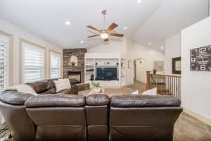 Living room with built in shelves, a fireplace, ceiling fan, and vaulted ceiling