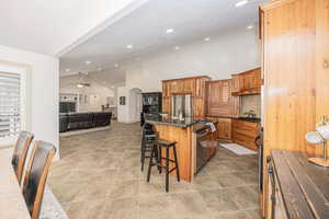 Kitchen with a breakfast bar, ceiling fan, stainless steel appliances, tasteful backsplash, and a center island with sink