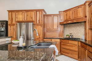 Kitchen featuring tasteful backsplash, appliances with stainless steel finishes, sink, and dark stone counters