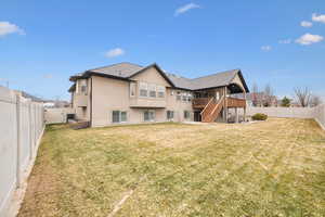 Back of house with a deck and a lawn