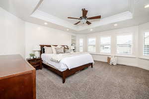 Bedroom with ceiling fan, a tray ceiling, and carpet flooring