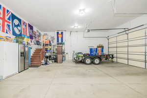 Garage with a garage door opener, stainless steel fridge with ice dispenser, and white fridge