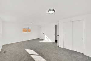 Unfurnished bedroom featuring a closet and dark colored carpet