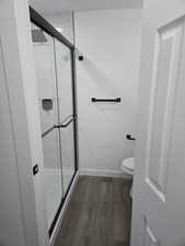 Bathroom featuring an enclosed shower, hardwood / wood-style flooring, and toilet