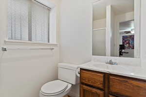 Bathroom featuring vanity, a shower with shower door, ceiling fan, and toilet