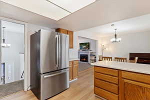 Kitchen featuring pendant lighting, a notable chandelier, stainless steel refrigerator, and light hardwood / wood-style floors