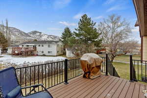 Snow covered deck with a mountain view, a shed, and a lawn