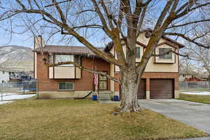 Bi-level home with a garage, a mountain view, and a front lawn