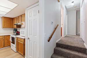 Kitchen with white appliances and light carpet