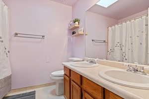 Bathroom featuring vanity, tile patterned flooring, a skylight, and toilet