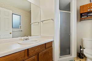 Bathroom with vanity, an enclosed shower, and toilet