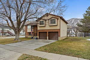 Split level home featuring a garage, a mountain view, and a front lawn