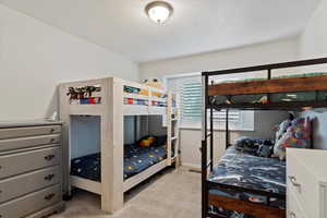 Bedroom featuring light colored carpet and a textured ceiling