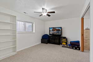 Sitting room with ceiling fan, light colored carpet, and a textured ceiling