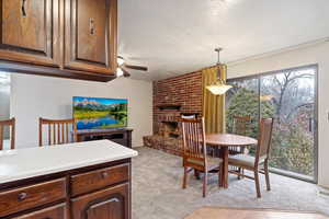 Carpeted dining room with ceiling fan, a textured ceiling, and a fireplace