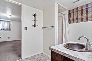 Bathroom with vanity, a shower with curtain, and a textured ceiling