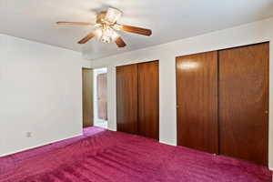 Unfurnished bedroom featuring multiple closets, carpet, and ceiling fan