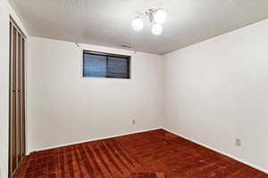 Carpeted spare room featuring a textured ceiling