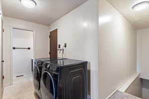 Washroom with washing machine and clothes dryer and a textured ceiling