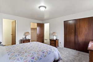 Carpeted bedroom with a spacious closet, a textured ceiling, and a closet