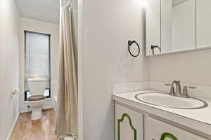 Full bathroom with shower / tub combo, vanity, hardwood / wood-style flooring, and toilet