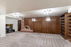 Interior space featuring carpet, a fireplace, a textured ceiling, and wood walls