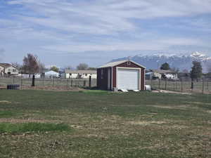 View of yard with a mountain view, fence, and an outdoor structure