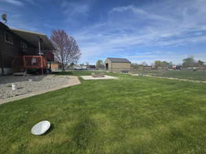 View of yard featuring a deck, fence, and an outdoor fire pit