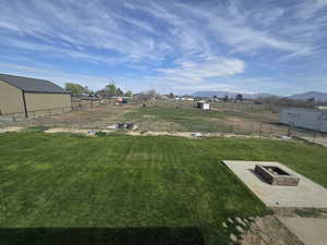 View of yard with a mountain view, an outdoor fire pit, fence, and an outdoor structure