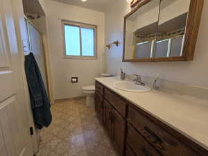 Bathroom featuring a shower with door, vanity, and toilet